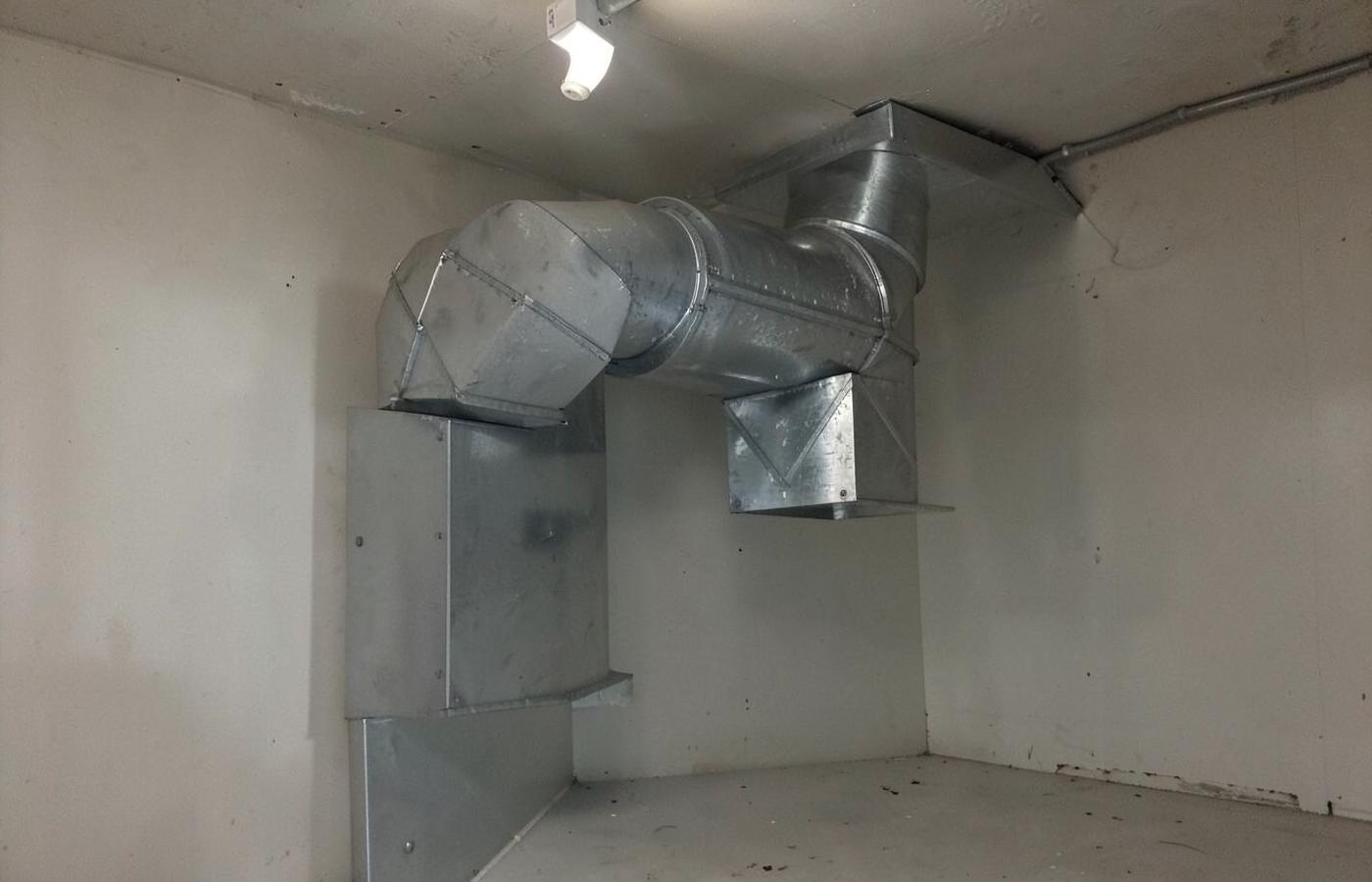 Galvanized sheet metal ductwork and plenum in a bare unfinished garage under work light