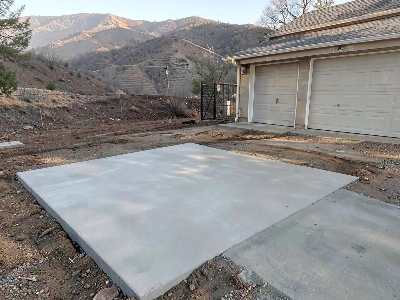 Freshly poured concrete driveway slab with wooden forms still in place beside a residential garage