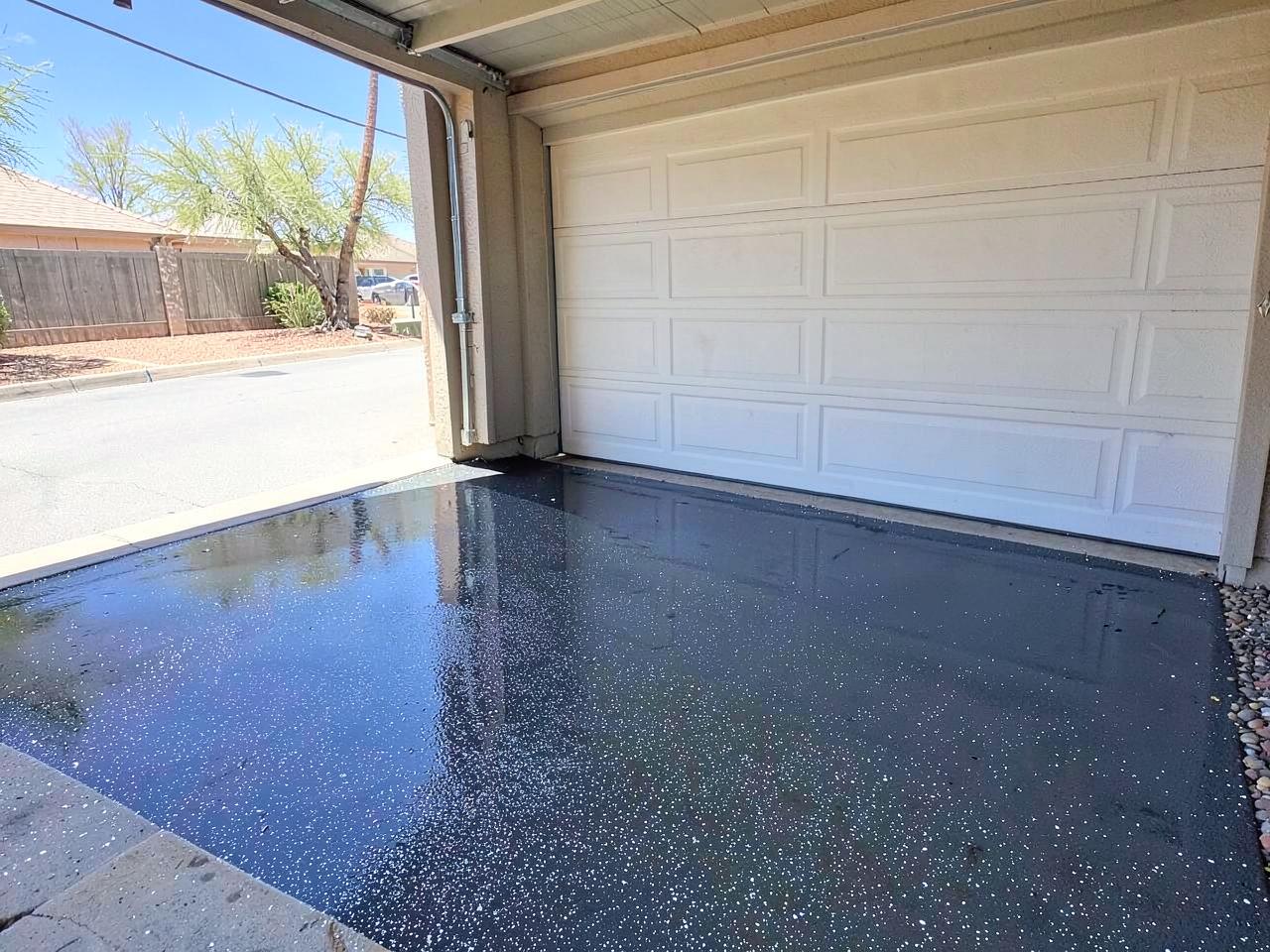 Glossy speckled epoxy-coated garage floor with the door open to bright desert daylight