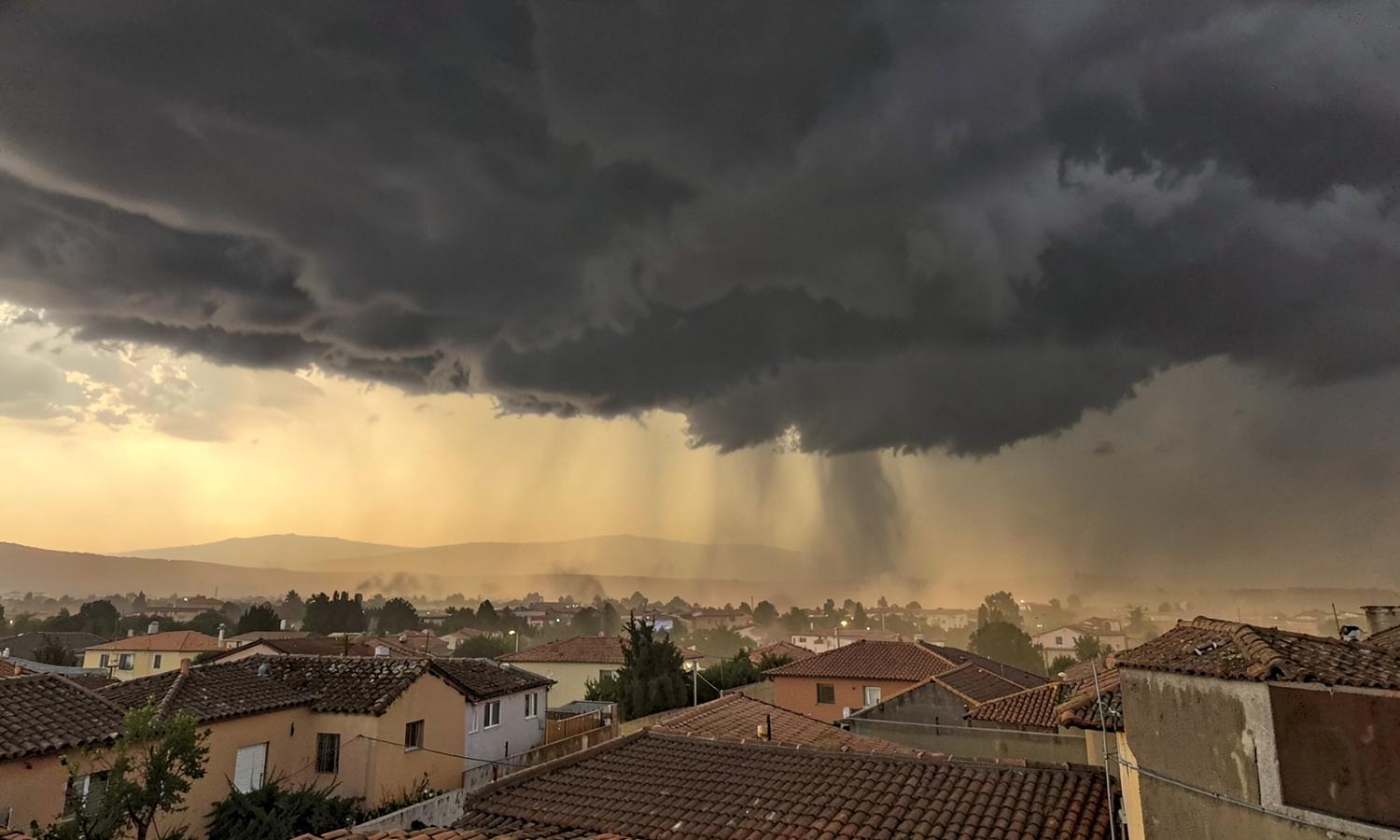 Dark monsoon storm clouds and a rain shaft moving over a desert neighborhood of tile-roof houses