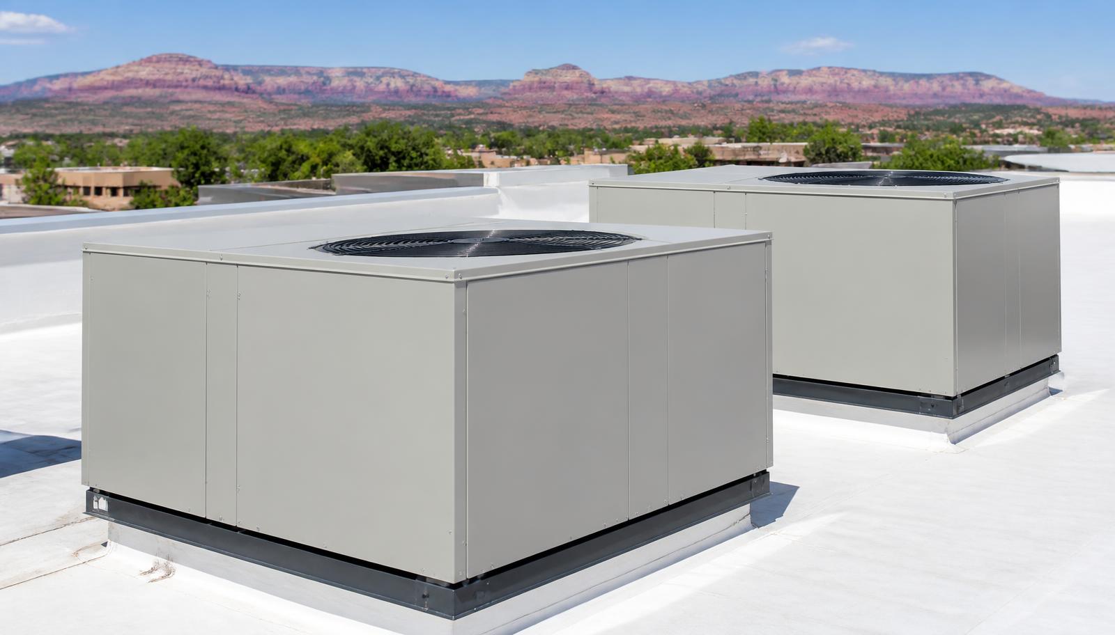 Technician servicing a rooftop air conditioning unit under triple-digit desert heat in St. George