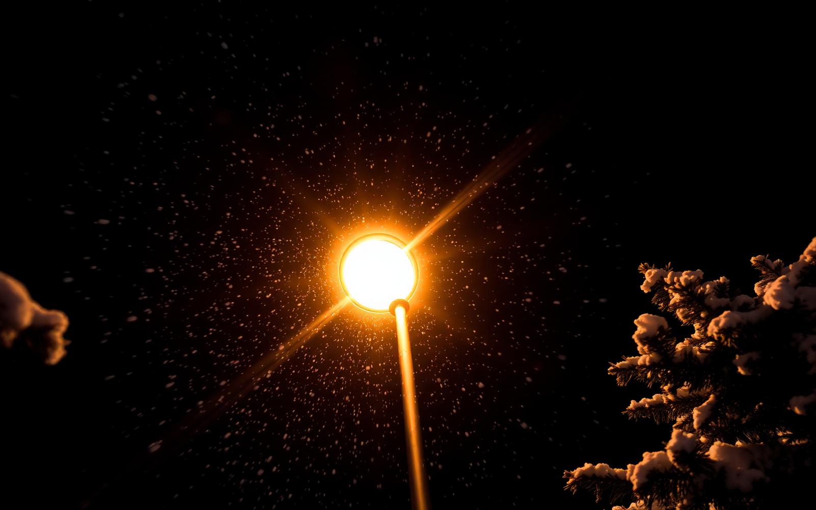 Heavy snowflakes streaking through the glow of a streetlamp on a quiet Park City street at night