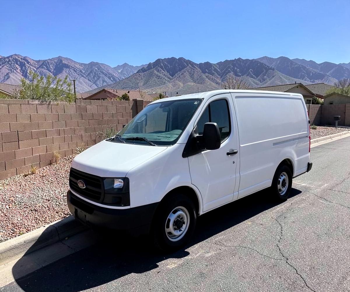 Plain white work van parked along a desert suburban street with block walls and bare mountains behind