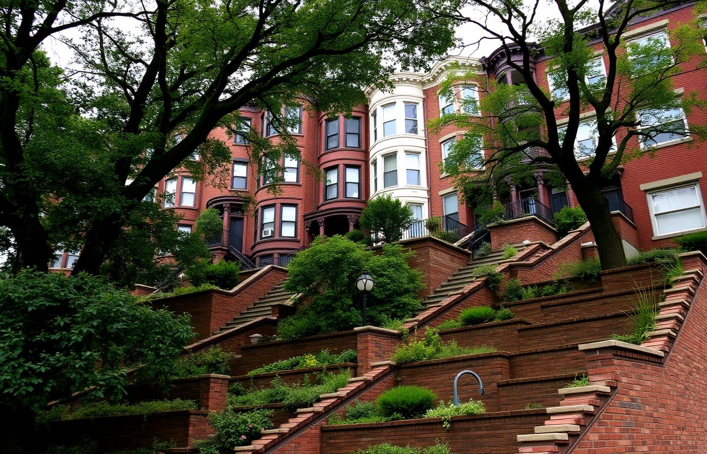 Brick row houses stacked up a steep urban hillside behind long flights of stone steps and retaining walls