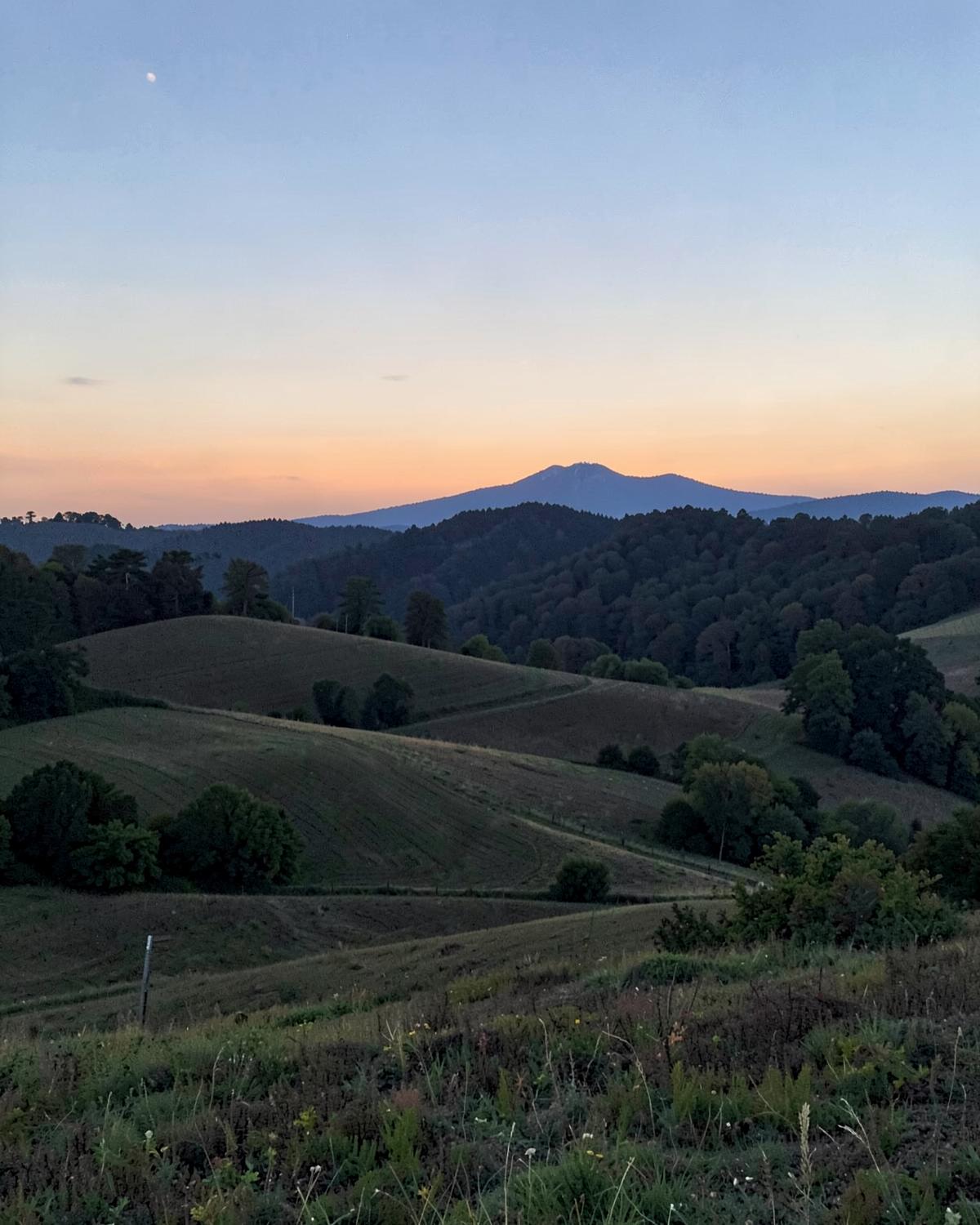 Blue Ridge foothills at dusk above rolling wooded ridges and open pasture in upstate South Carolina