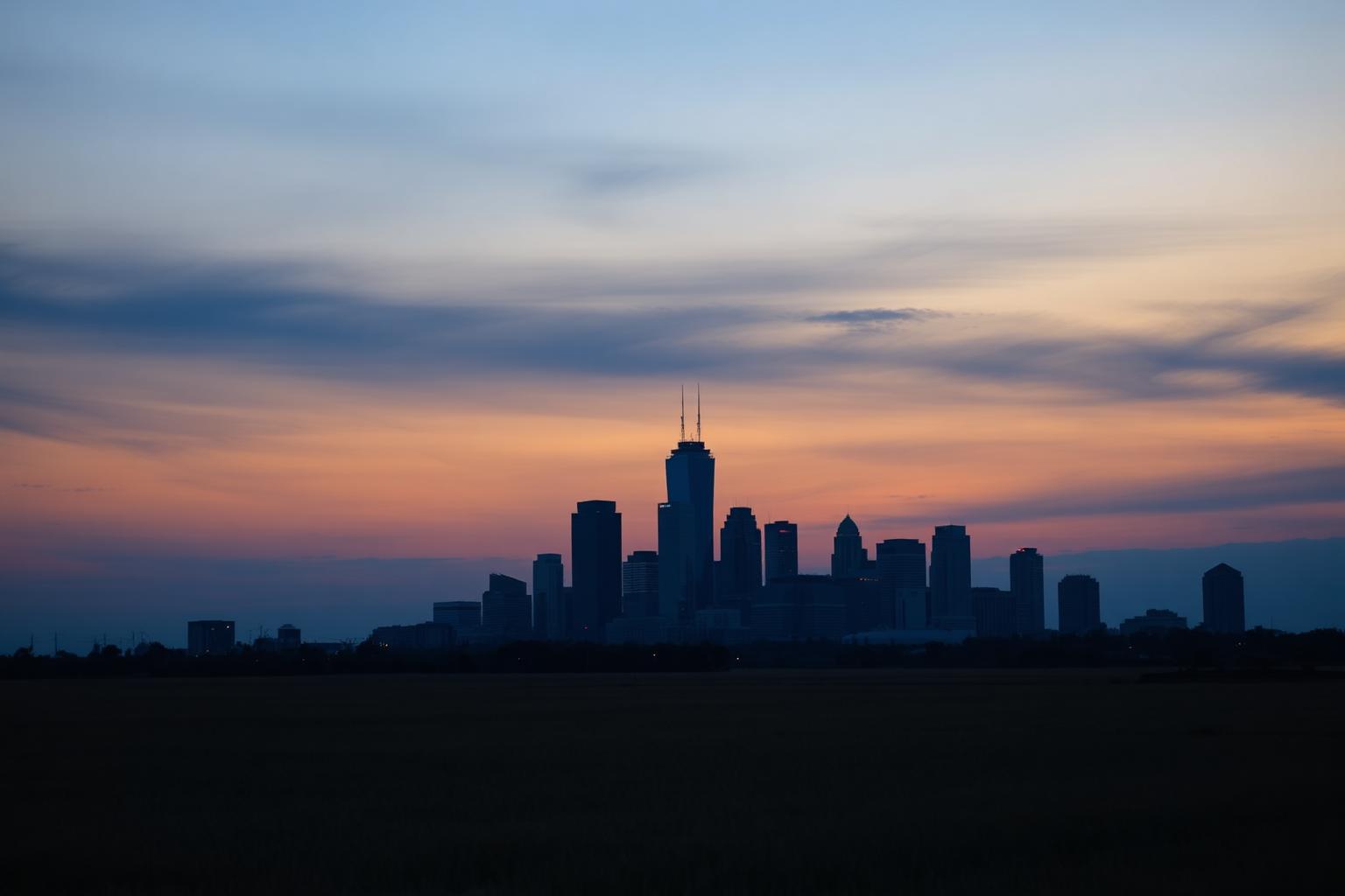 Dallas, Texas downtown skyline silhouetted at dusk across open North Texas prairie