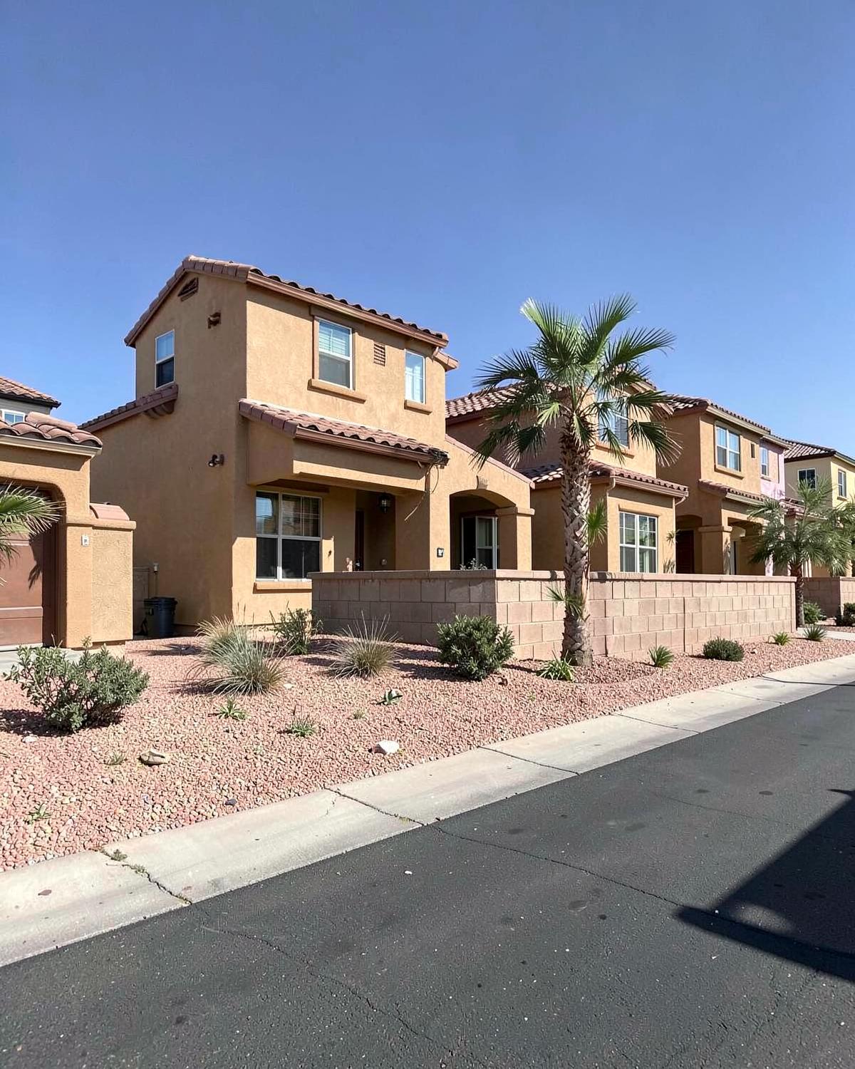 Newly built single-story stucco homes with tile roofs and gravel desert landscaping on a quiet street