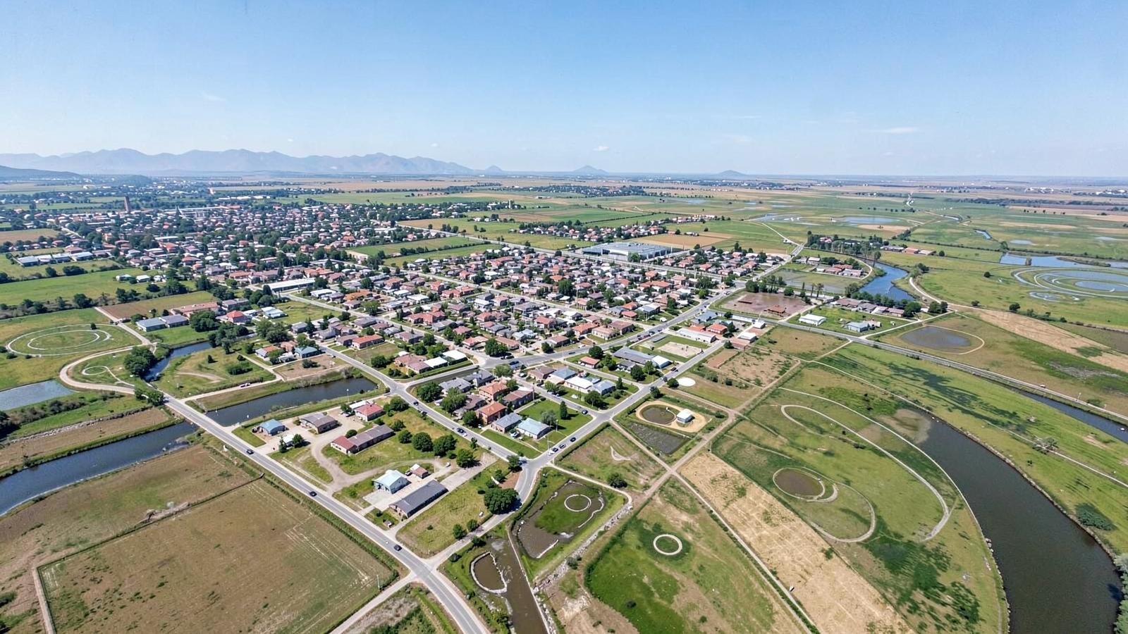 Aerial view of a small high-plains city along a river surrounded by farm fields and irrigation circles