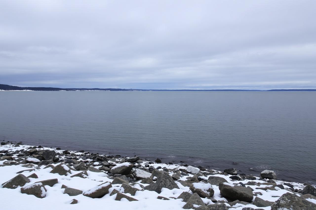 Snow-covered rocky shoreline of a large lake under low winter clouds