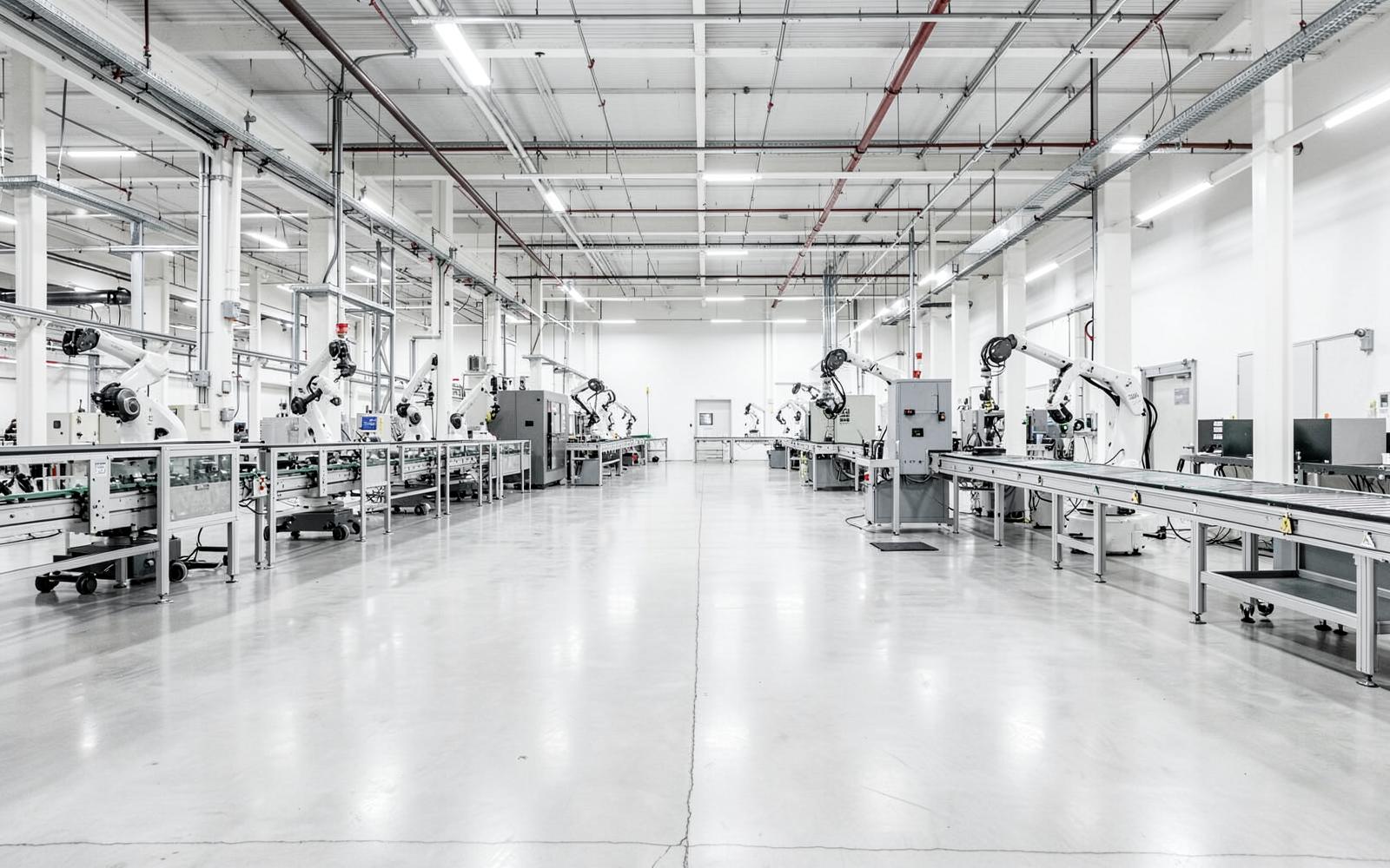 Bright modern manufacturing plant interior with robotic arms and conveyor lines on a polished concrete floor