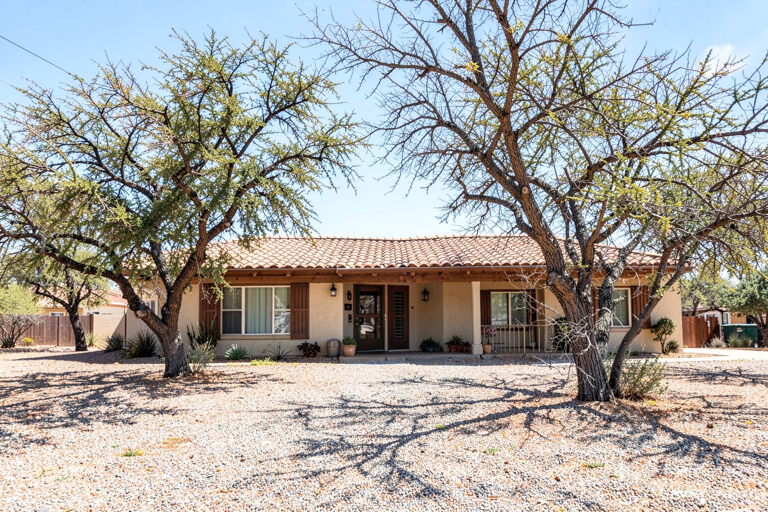 Mid-century ranch home with tile roof and mature mesquite trees in an established desert neighborhood