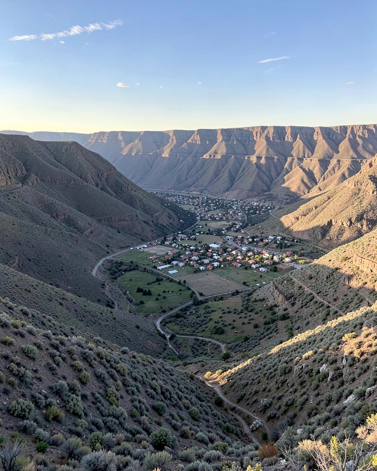 Wide aerial view of a small city on a valley floor between dry sagebrush mountain ranges