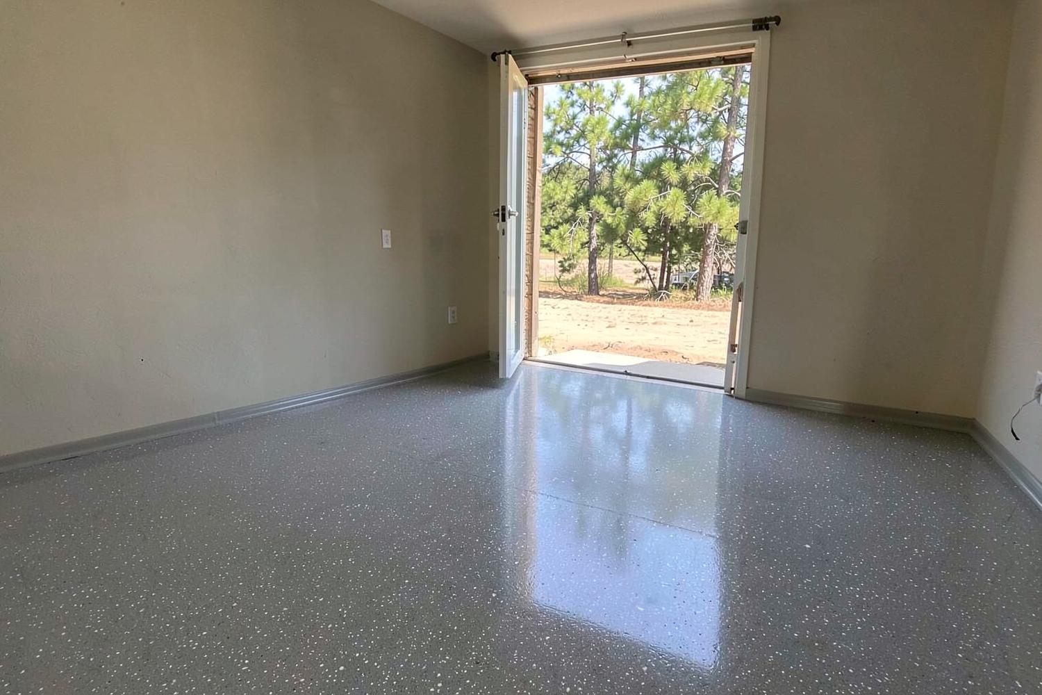 Glossy grey coated garage floor in an empty residential garage with clean bare walls