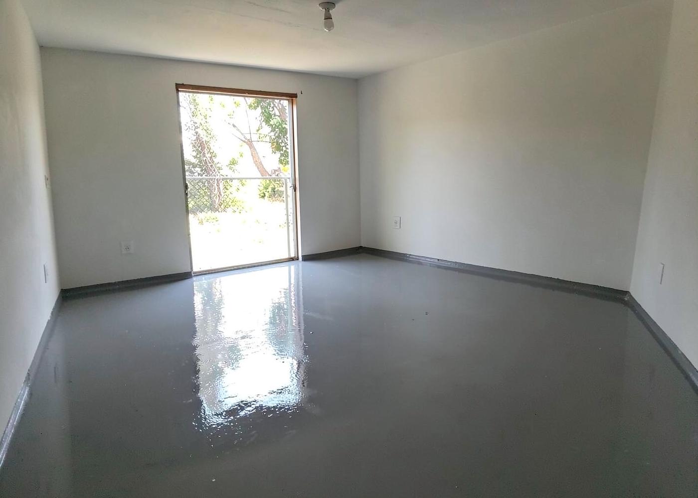 Residential garage interior with a freshly poured glossy grey epoxy coated floor reflecting daylight from the open door