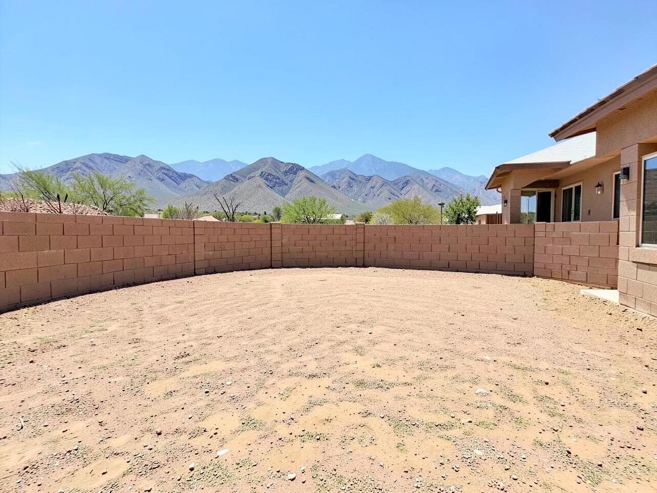 Bare graded dirt backyard of a new desert home enclosed by a block wall with mountain views