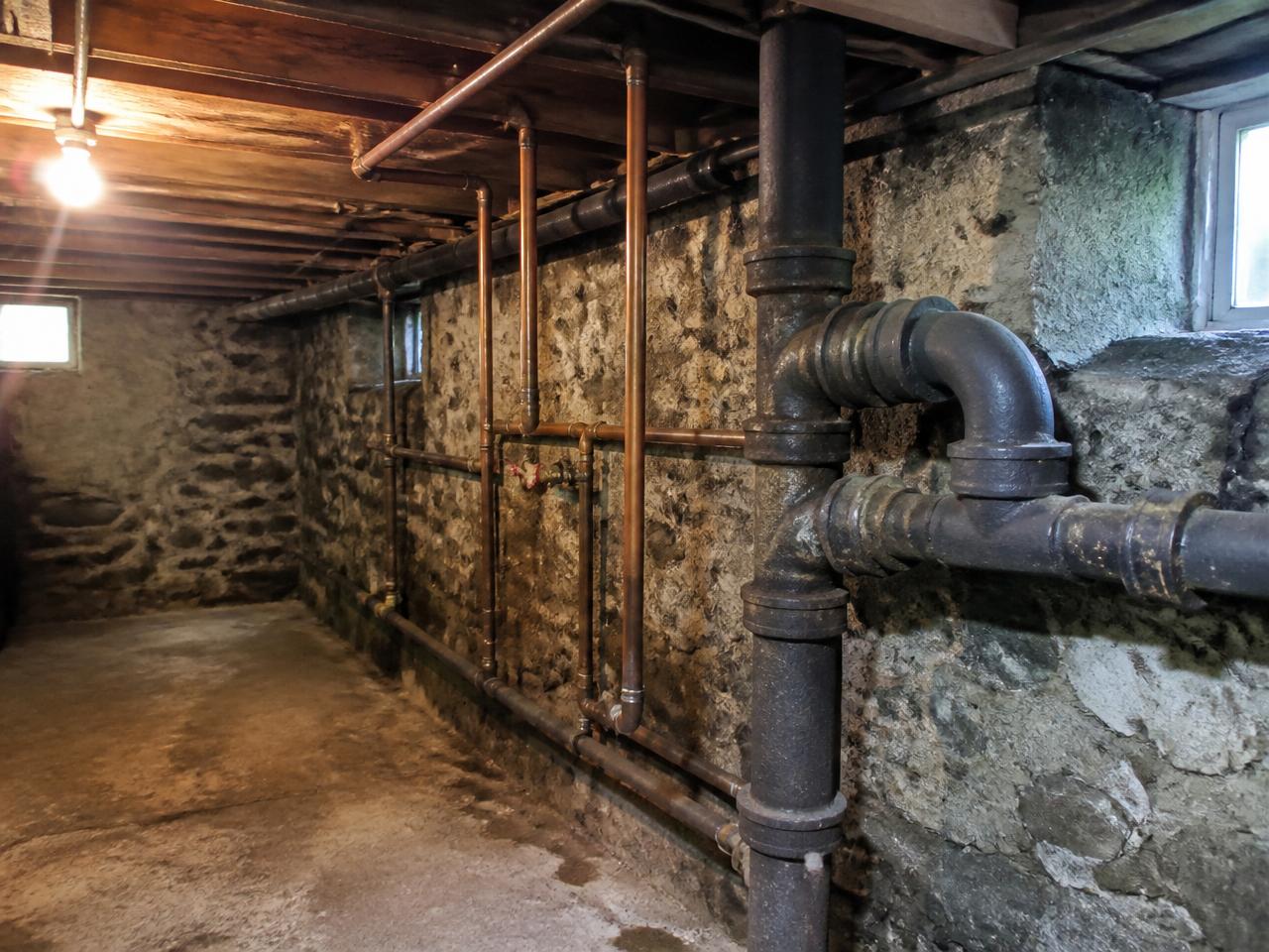 Exposed plumbing pipes running through a tight Pittsburgh basement