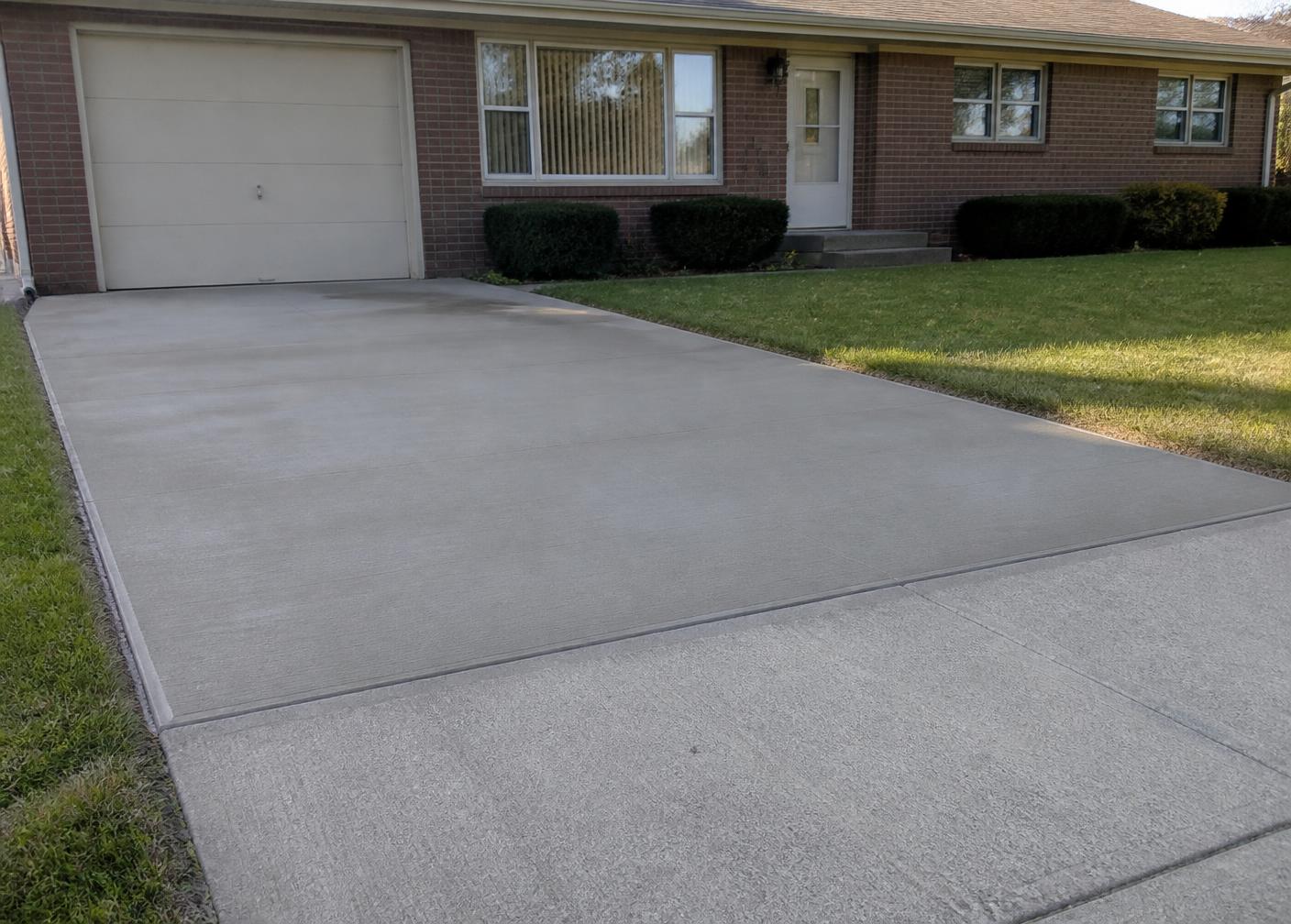Close-up of a concrete driveway repair in progress at a 1970s rambler-style home