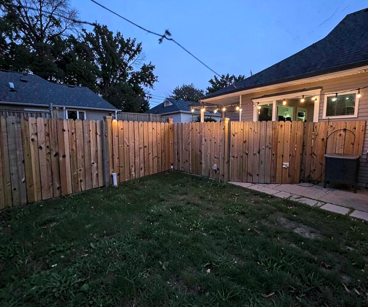 New wooden privacy fence along the back yard of a suburban home with fresh grass