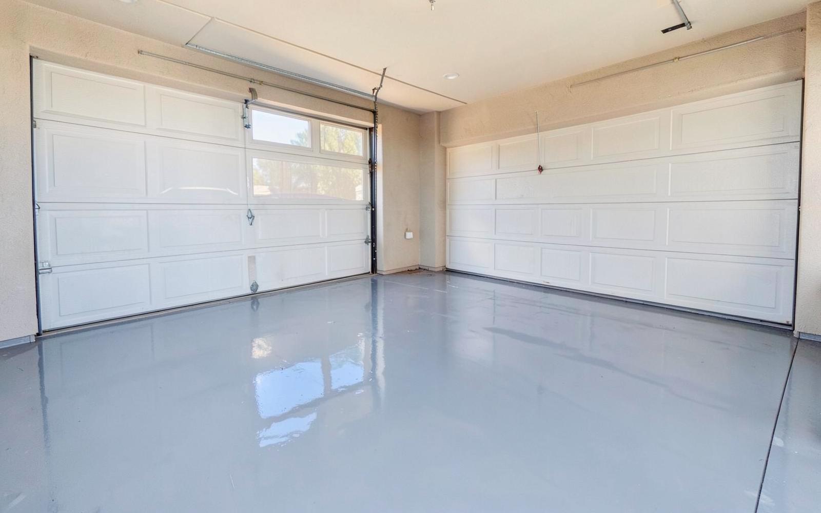 Glossy gray epoxy-coated garage floor in a clean desert home garage with the door open to bright sunlight