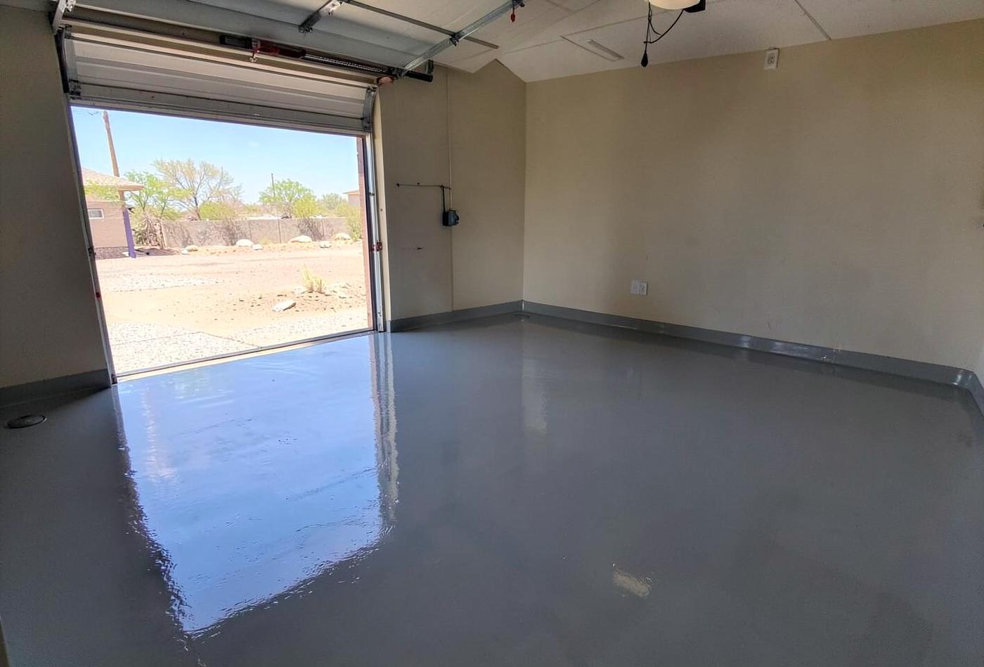 Freshly coated glossy grey epoxy garage floor in a clean residential garage with sunlight across the surface