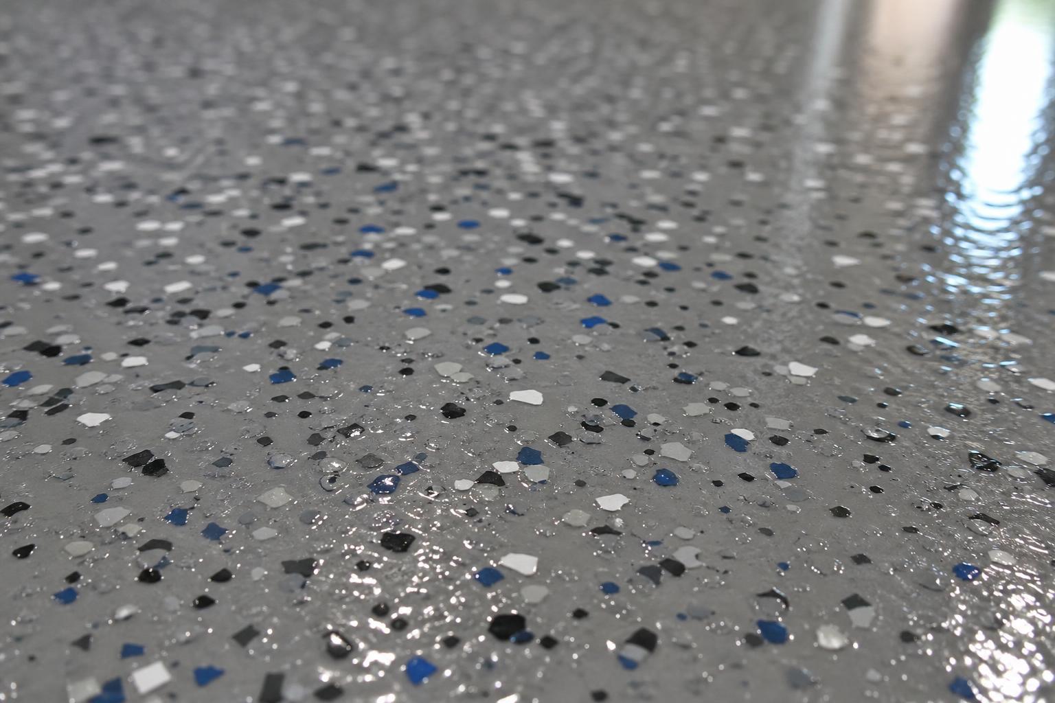 Close-up of a glossy grey epoxy garage floor coating with colored flake chips in an Orlando home