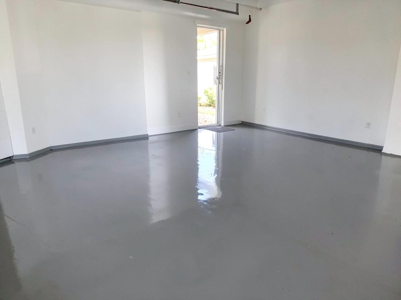 Glossy grey epoxy-coated garage floor reflecting light in a clean empty garage