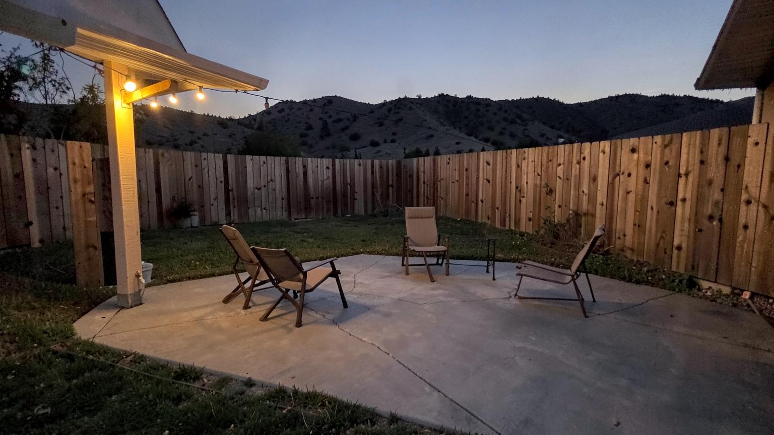 Stamped concrete patio with outdoor furniture glowing under warm string lights at dusk