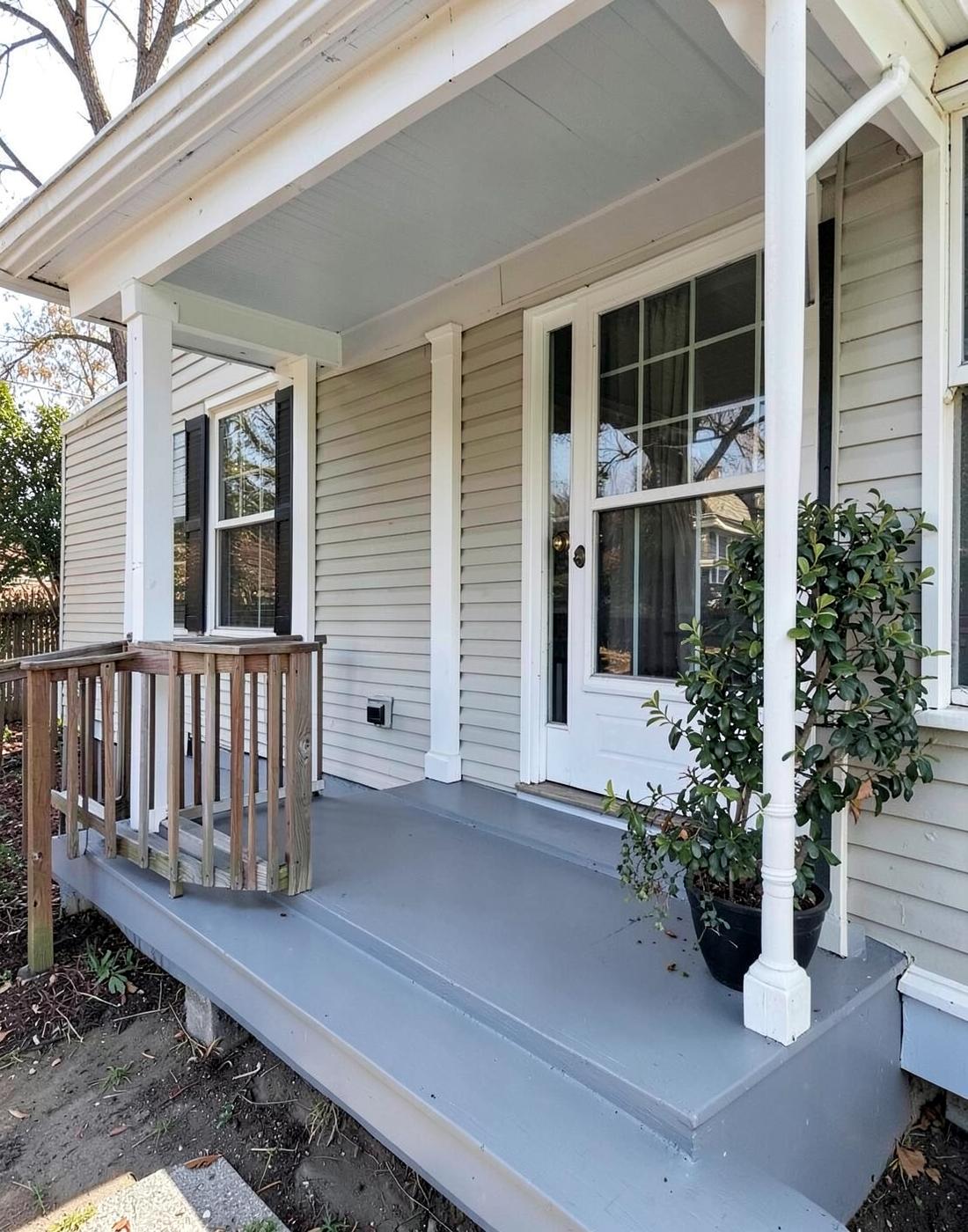 Freshly repainted front porch of an older home with clean white trim and a new grey painted floor