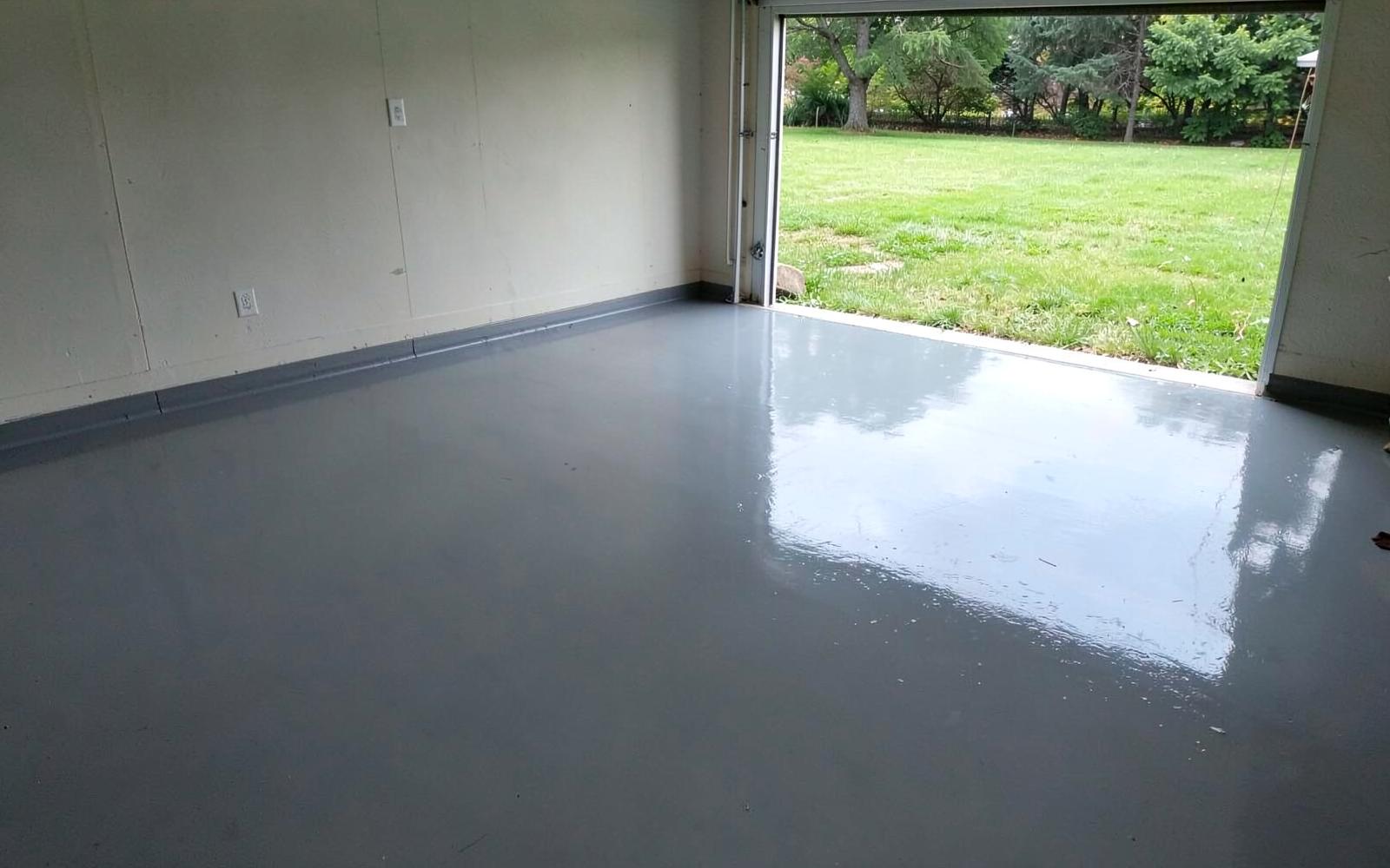 Freshly coated glossy grey epoxy garage floor with clean walls and an open garage door