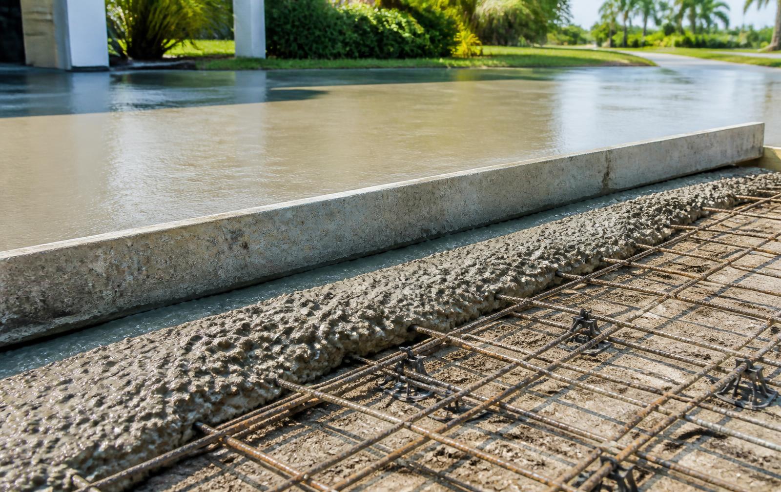 Freshly poured concrete driveway slab with rebar mesh visible at the edge on a Tampa job site
