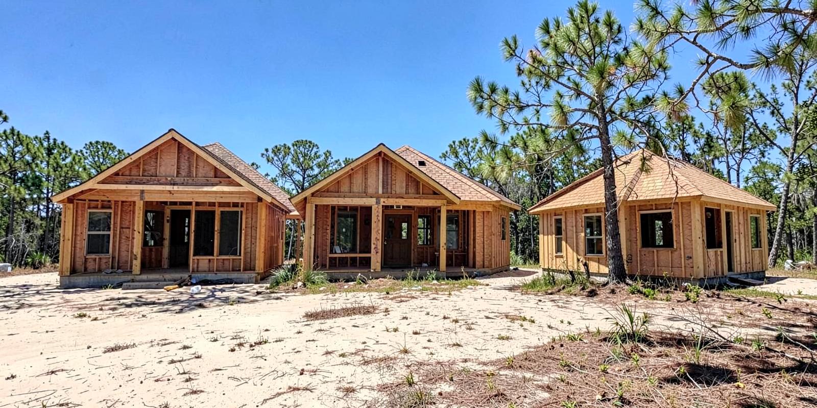 Wood-framed new construction houses on sandy lots in a Lowcountry subdivision edged by pines